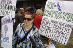 Former Enron employee Sonia Garcia holds up protest signs at a rally sponsored by the Reverend Jesse Jackson 